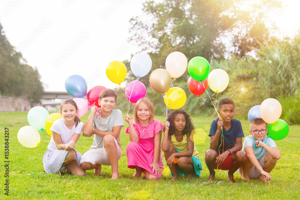 Obraz premium Group photo of happy children playing on lawn with balloons in hands.