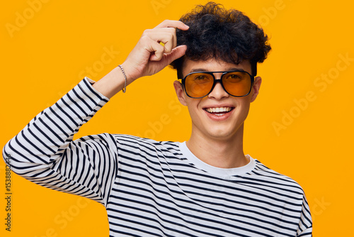Photos smiling man wearing striped shirt and sunglasses posing against bright orange ba