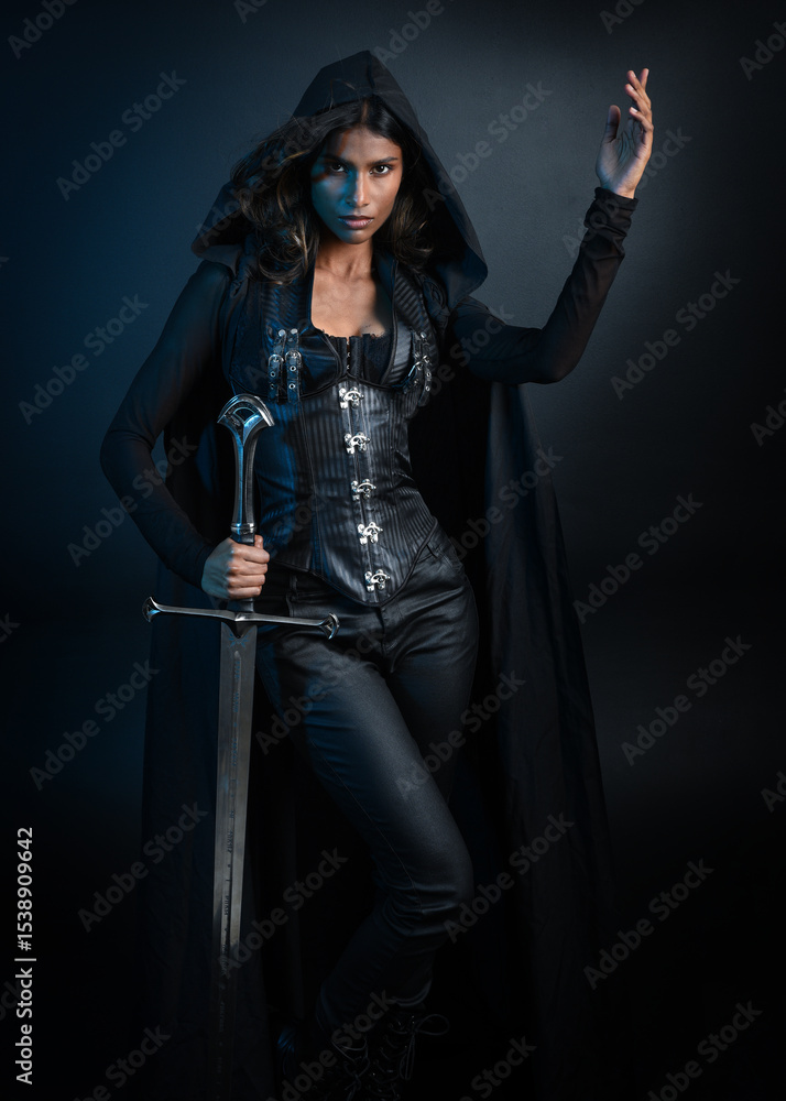 portrait of mysterious hooded woman in black cloak, gothic fantasy or dystopian character, holding sword weapon. lit with moody cinematic shadows, studio scene on dark isolated background portrait of mysterious hooded woman in black cloak, gothic fantasy or dystopian character, holding sword weapon. lit with moody cinematic shadows, studio scene on dark isolated background