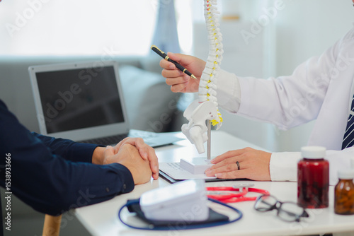 An orthopedic doctor shows a spinal model to a patient in a human spinal hospital. Diseases and disorders of the spinal cord, back pain, lumbar pain, orthopedic surgery, chiropractic, office syndrome