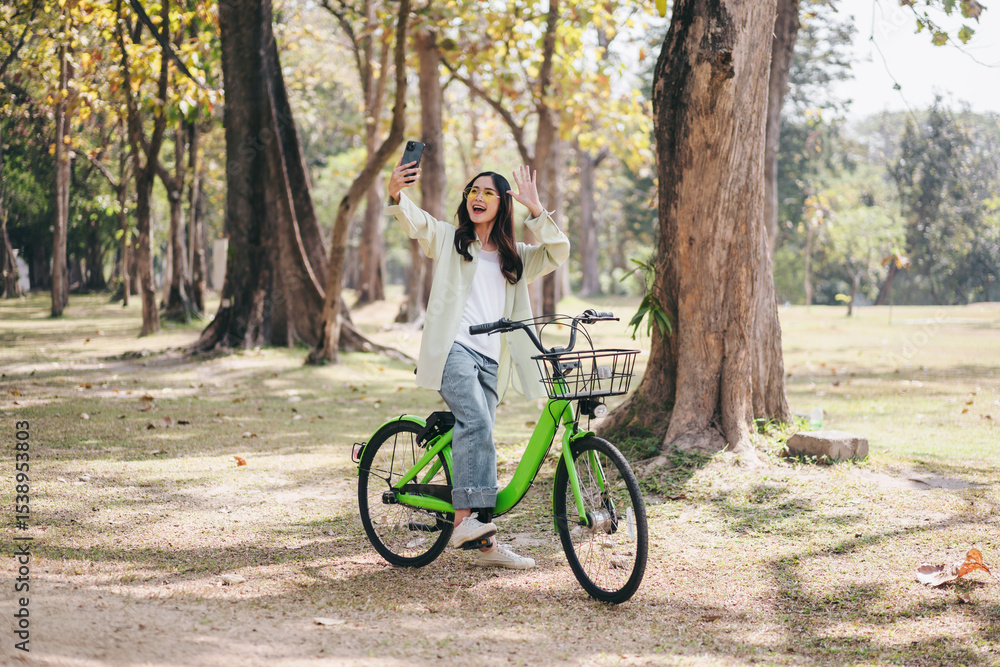 Fototapeta premium A woman is riding a green bicycle in a park