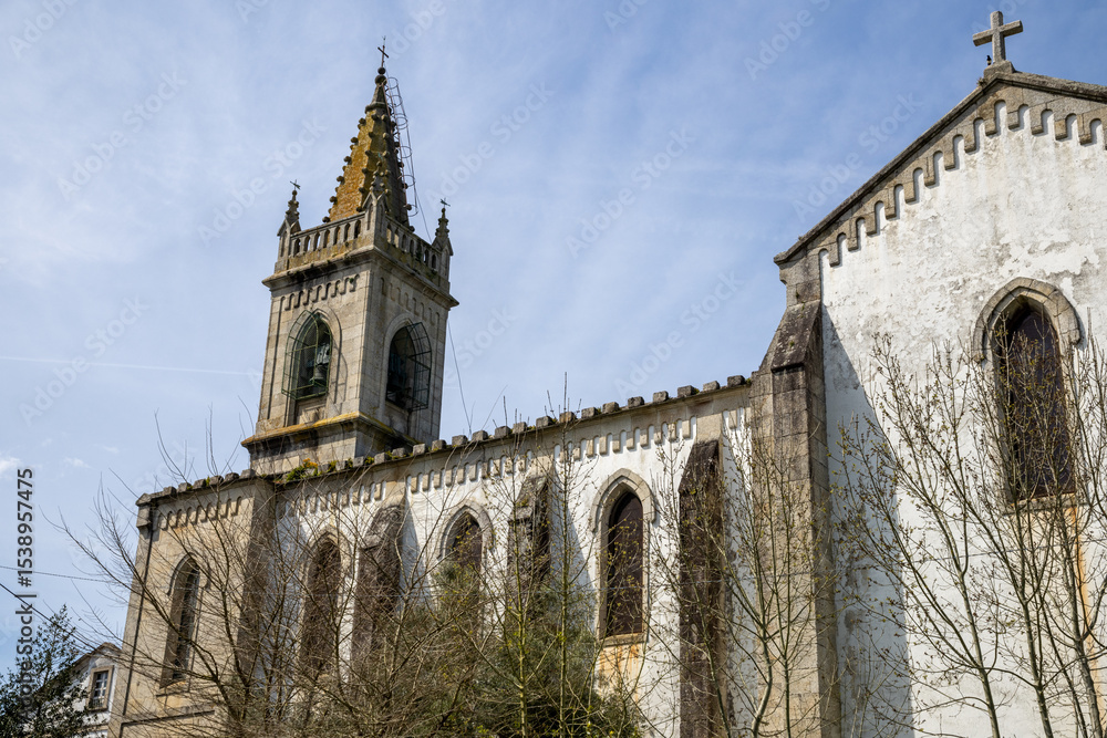 Fototapeta premium Neo-Gothic Church of Santiago in Mondoñedo, Lugo, Galicia, Spain. Historic architecture under clear skies in a quiet town square.