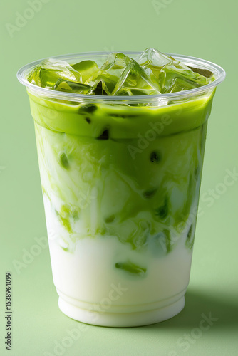a transparent plastic cup filled with iced matcha latte each drink features two distinct layers: bright green matcha on top and creamy white milk at the bottom no strawberry or fruit layers, just a cl