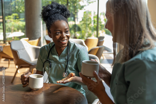 Female doctors sitting in a cafe while coffee break and discussing something