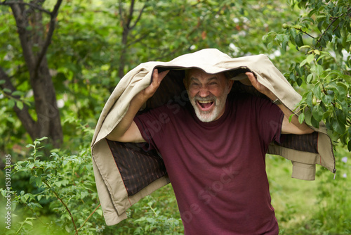 Foto Summer rain catches a grown man by surprise in the garden