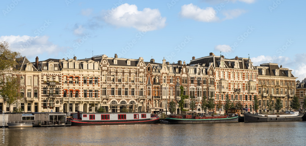 Fototapeta premium Panorama with historic apartments along the Amstel River in the center of Amsterdam.