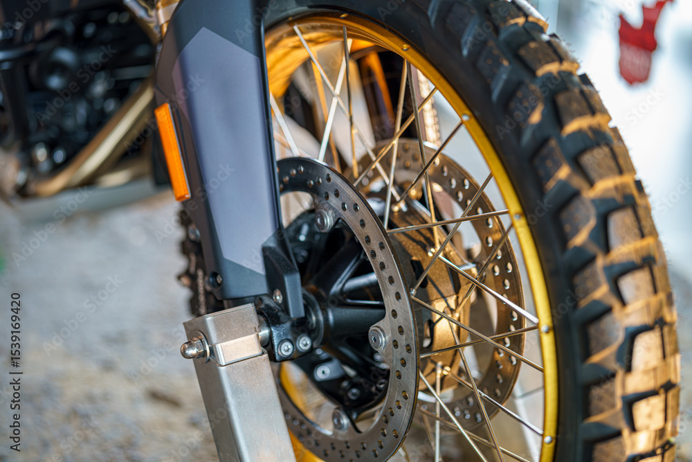 Fototapeta premium Detailed close-up of a motorcycle wheel showing brake system and tire tread patterns in a workshop setting