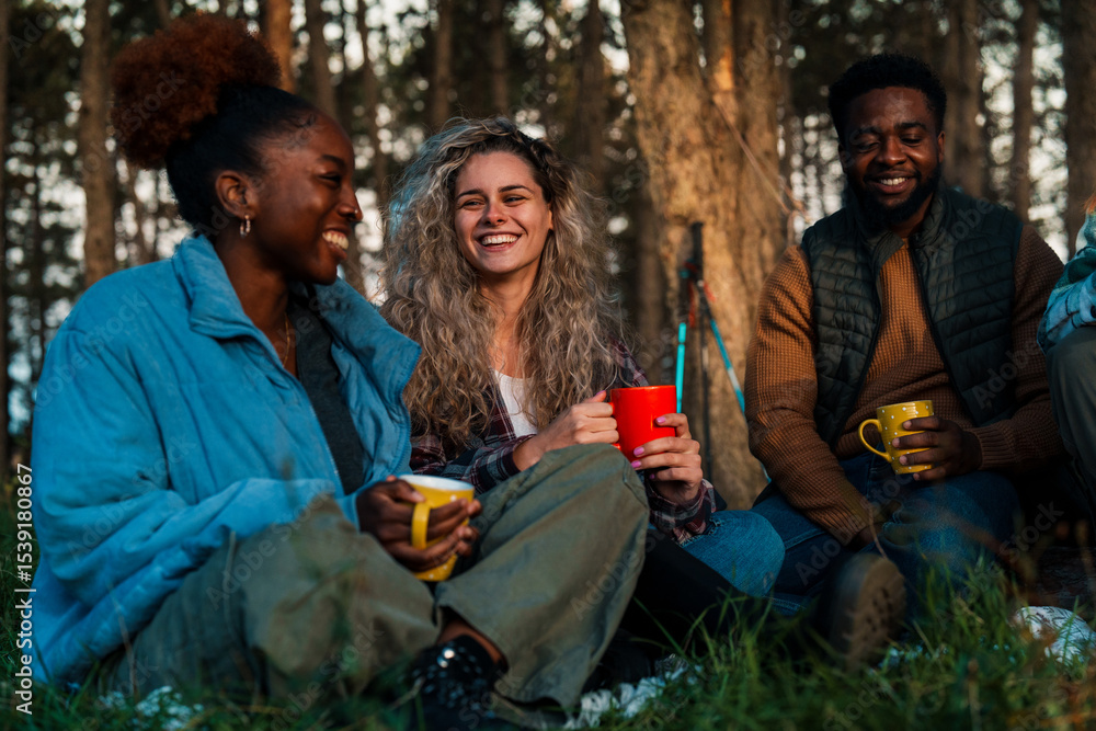 Fototapeta premium Sunset camping scene with friends sharing stories over colorful mugs. Natural lifestyle photo showing genuine smiles and diverse outdoor connections.