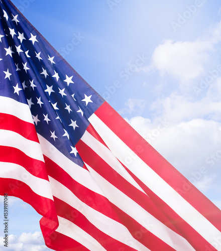 Waving American Flag Against Blue Sky. Symbol of Freedom and Patriotism. Stock photo.