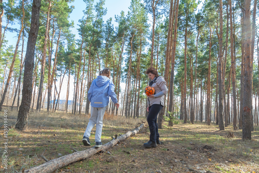 Grandmother and granddaughter walking with a ball in the forest in sunny day. Grandmother and granddaughter walking with a ball in the forest in sunny day.