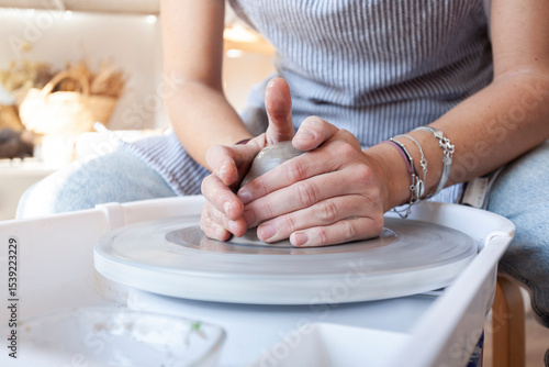 Hands of a ceramic artist centering clay on pottery wheel in artisan studio