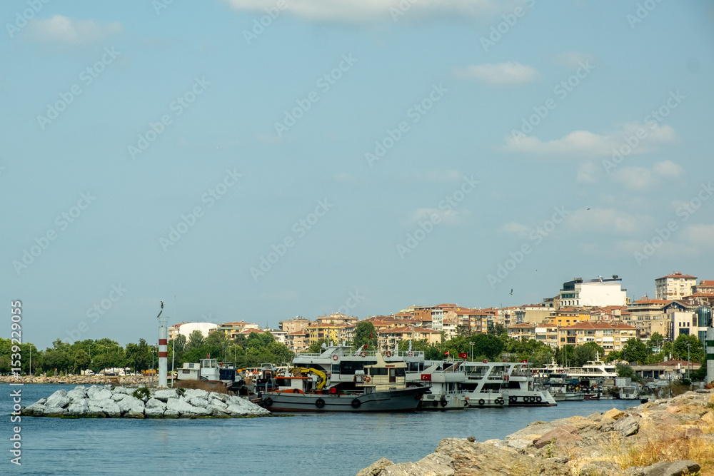 Fototapeta premium Bustling Kartal Marina in Istanbul Turkey with Colorful Fishing Boats, Luxury Yachts and Sailboats Moored in Sunny Mediterranean Harbor with Rocky Coastline