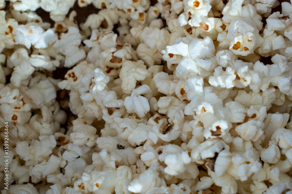 Close-up of freshly popped white popcorn kernels in a wooden bowl under natural sunlight. Concept of snack food, movie night, homemade treats, and tasty crunchy texture in high detail. Close-up of freshly popped white popcorn kernels in a wooden bowl under natural sunlight. Concept of snack food, movie night, homemade treats, and tasty crunchy texture in high detail.