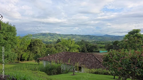 Scenic panning shot of a peaceful countryside farm near Lake Calima in Valle del Cauca, Colombia, showing lush green fields, serene landscape, and majestic surrounding mountains under daylight