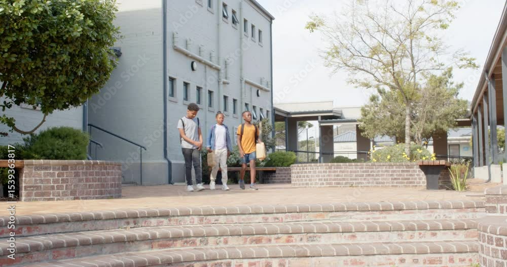 Walking outside school, multiracial students carrying backpacks and chatting happily Walking outside school, multiracial students carrying backpacks and chatting happily