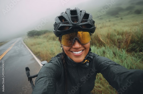 Fototapeta Naklejka Na Ścianę i Meble -  Woman cyclist smiles on a rainy road