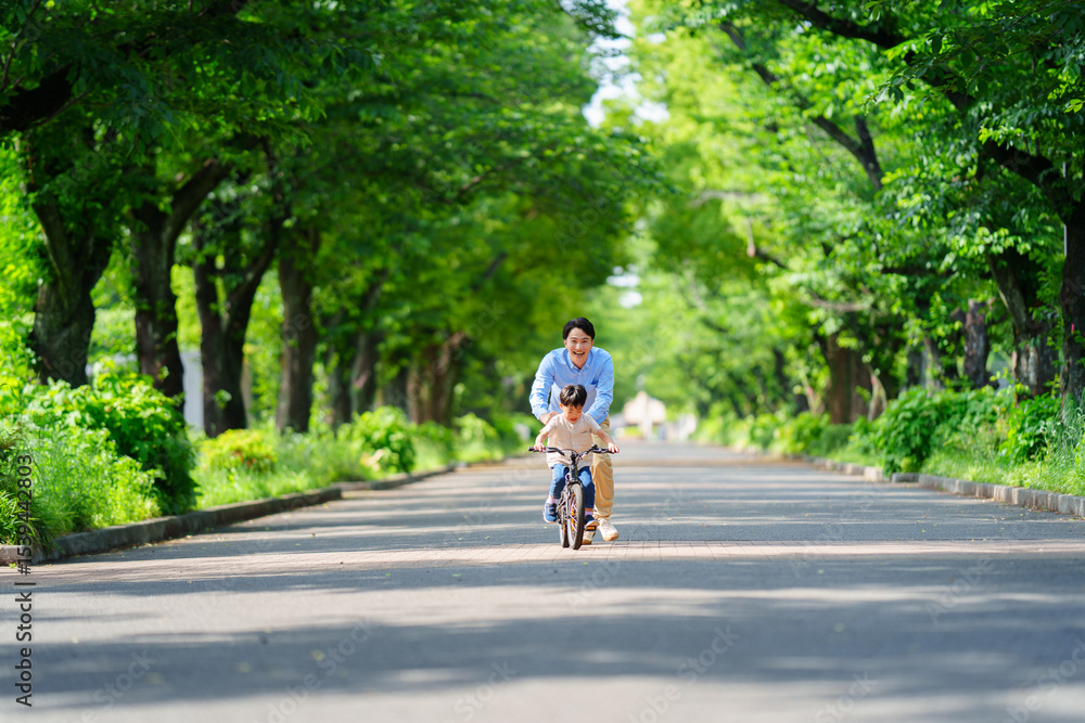 Obraz premium 両親と自転車の練習をする5歳の少年