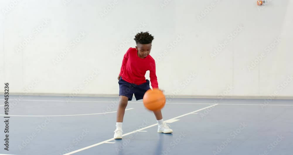 Practicing basketball dribbling, african american boy focused on indoor court, copy space Practicing basketball dribbling, african american boy focused on indoor court, copy space