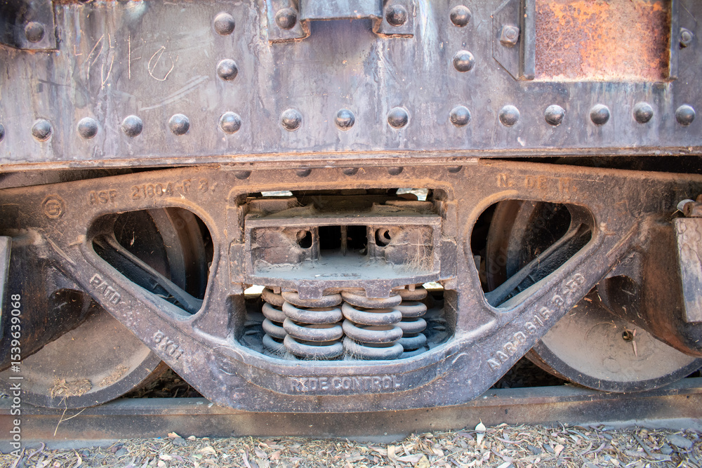 Fototapeta premium Detailed view of an old rusty train wheel suspension with visible springs and bolts in daylight