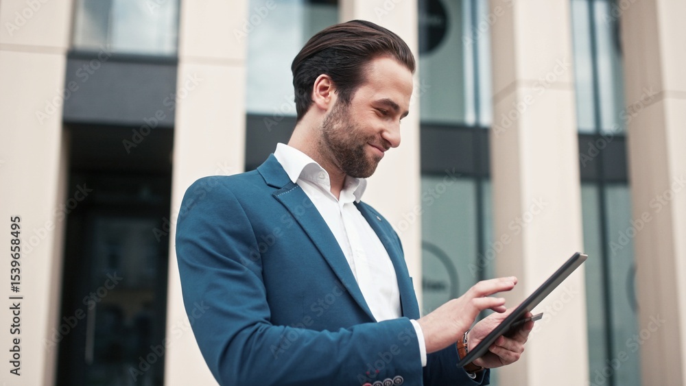 Fototapeta premium Boss of company standing outside near office building. Company director holding tablet. Executive director conducting transaction outdoor. Leader of company holding credit card.
