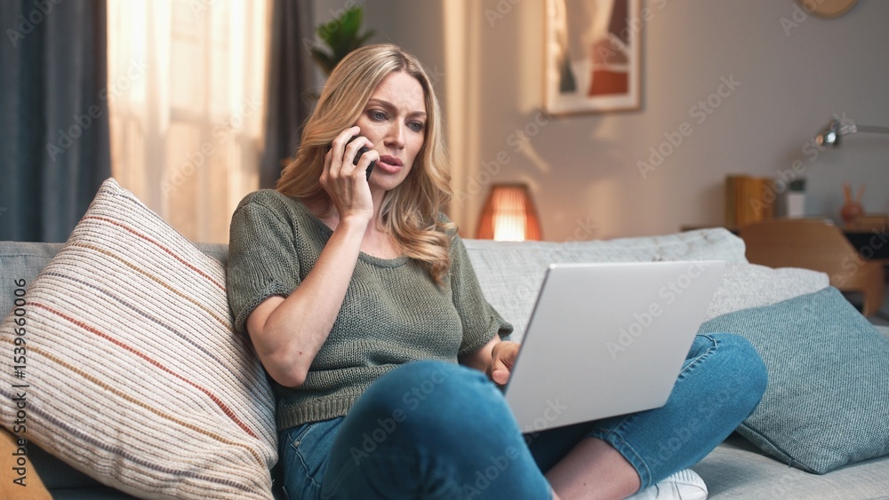 Fototapeta premium Yound beautiful woman working from home online freelance sitting on couch using laptop and smartphone. Pretty female calling clients typing on computer using technologies. Working from home concept.