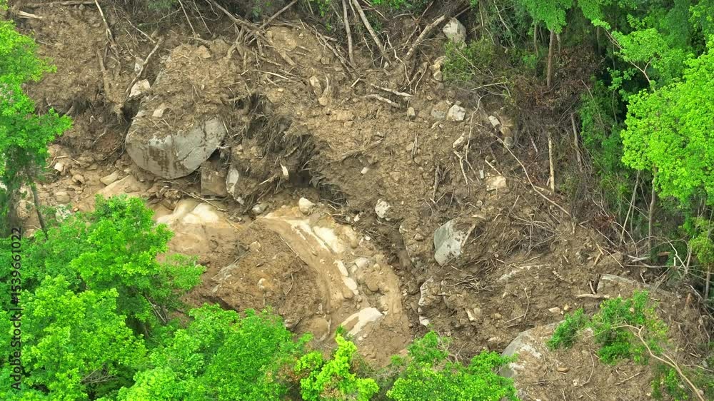 Drone aerial view of a landslide area showing uprooted trees, mud, and debris, highlighting the destructive power of natural disasters on forested landscapes and ecosystems. Thailand.
Drone aerial view of a landslide area showing uprooted trees, mud, and debris, highlighting the destructive power of natural disasters on forested landscapes and ecosystems. Thailand.