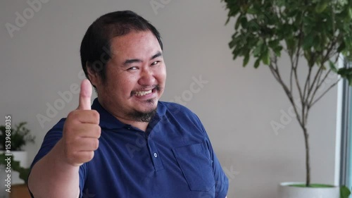 Happy smiling Asian middle aged old man showing approving, passing, good, yes, go for it, good to go, thumb up hand gesture to his side