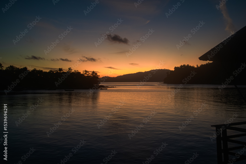 Naklejka premium Serene Sunset Over Tropical Bay with Silhouetted Pier and Islands