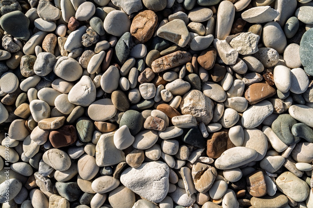 Naklejka premium A close-up of smooth beach stones, showcasing nature s artistry. The rounded stones in calming earth tones create a textured, tranquil scene perfect for highlighting natural beauty.