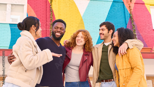 Group of multiethnic young people smiling and having fun in front of colorful wall