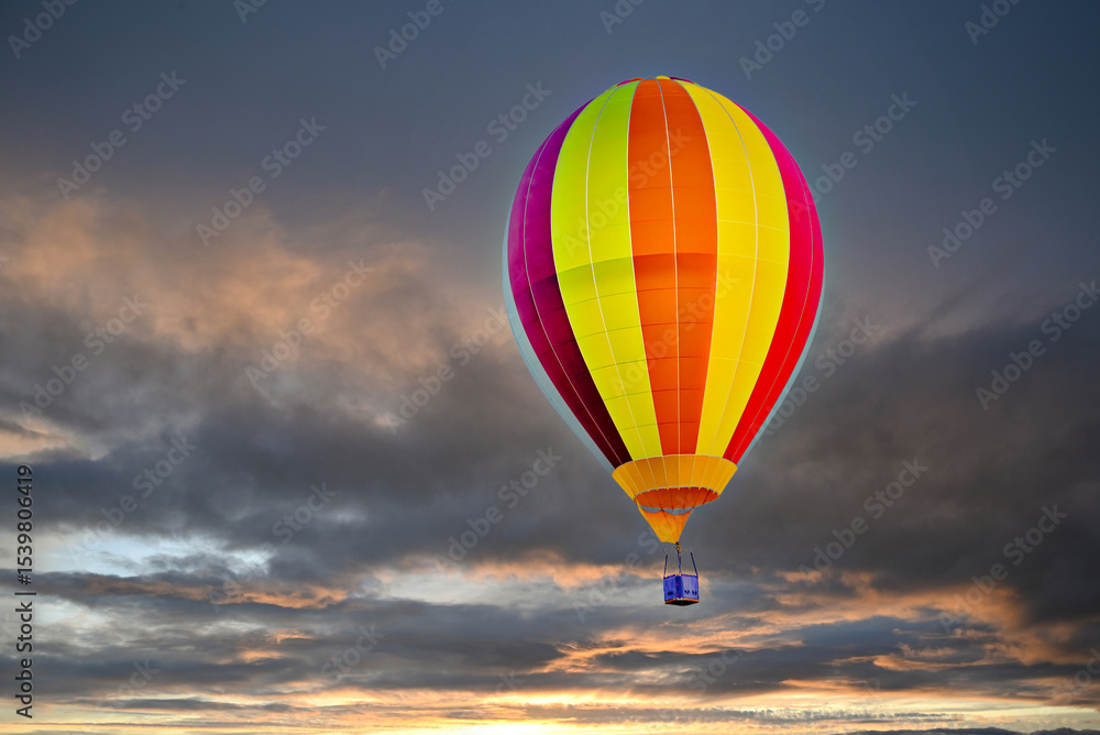 Obraz premium Colorful hot air balloon flying under orange sunset sky