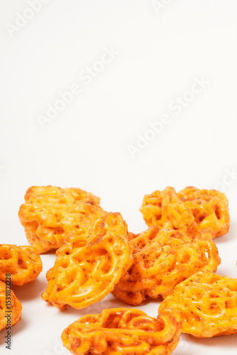 A pile of spicy Indonesian crackers or Kerupuk with spiral twists, coated in red-orange chili powder and rich spices. Bold, flavorful, and appetite-boosting. Photographed against a white background.