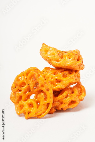 A pile of spicy Indonesian crackers or Kerupuk with spiral twists, coated in red-orange chili powder and rich spices. Bold, flavorful, and appetite-boosting. Photographed against a white background.