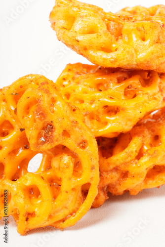 A pile of spicy Indonesian crackers or Kerupuk with spiral twists, coated in red-orange chili powder and rich spices. Bold, flavorful, and appetite-boosting. Photographed against a white background.