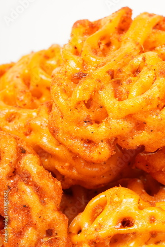 A pile of spicy Indonesian crackers or Kerupuk with spiral twists, coated in red-orange chili powder and rich spices. Bold, flavorful, and appetite-boosting. Photographed against a white background.