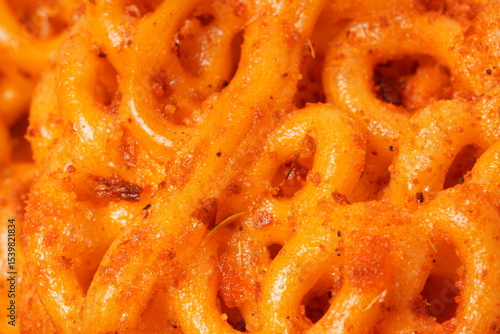 A pile of spicy Indonesian crackers or Kerupuk with spiral twists, coated in red-orange chili powder and rich spices. Bold, flavorful, and appetite-boosting. Photographed against a white background.