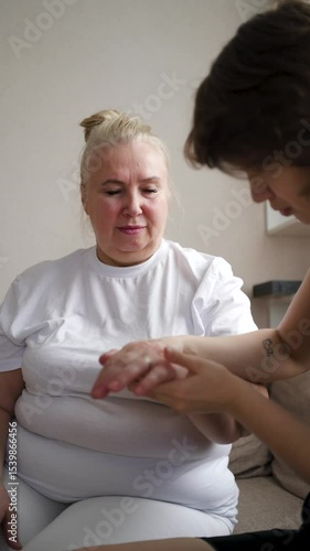 A thoughtful daughter helps her mother ease back and joint pain with a gentle massage. A tender, relaxing family moment showing love, care, and support in everyday home life