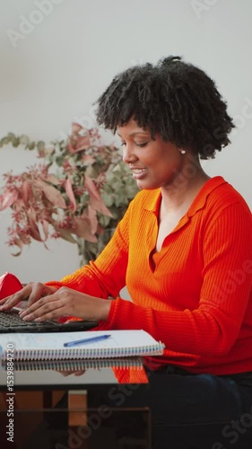 Motivated female student actively typing on her laptop, diligently working on homework and academic tasks at her tidy desk, showcasing dedication and concentration in a comfortable home workspace