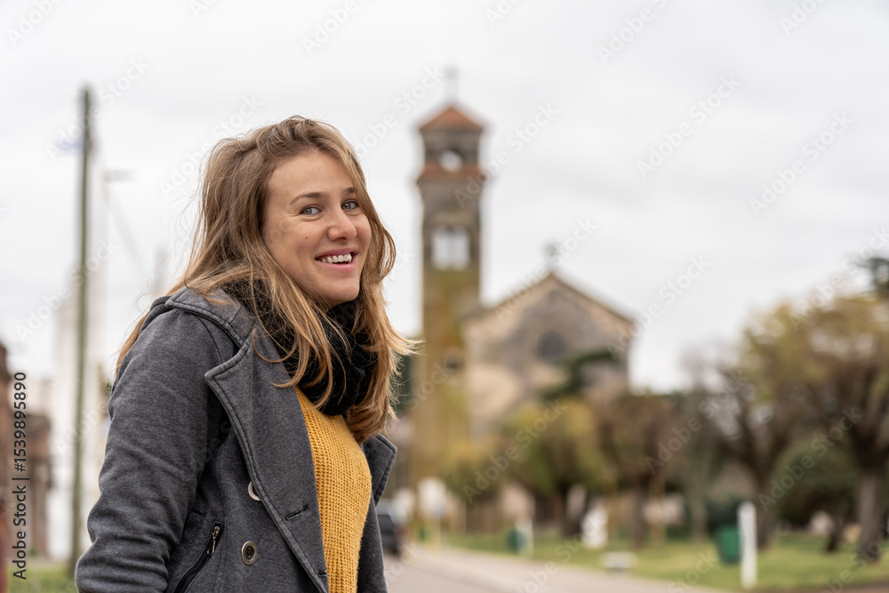 Fototapeta premium Woman standing on quiet street with historic church behind
