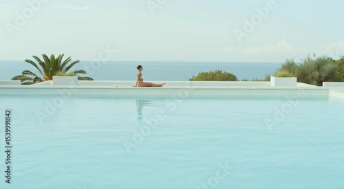 Woman relaxing by pool with ocean view