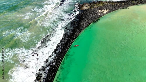 Drone view of canoeists enjoying their time in a tidal pool in Cape Town South Africa with the ocean waves in the background