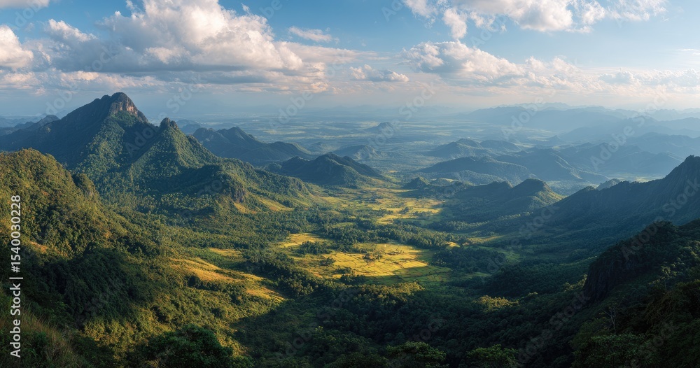 Obraz premium Panoramic vista of a verdant valley nestled amongst majestic, sun-dappled mountains under a partly cloudy sky
