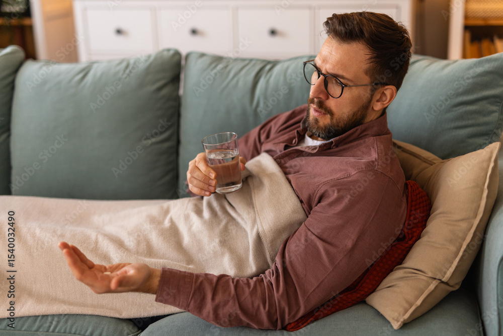Sick Man takes medication prescribed by his physician. Unwell Man taking a pill and drinking a glass of water. Health, medicine, treatment concept Sick Man takes medication prescribed by his physician. Unwell Man taking a pill and drinking a glass of water. Health, medicine, treatment concept