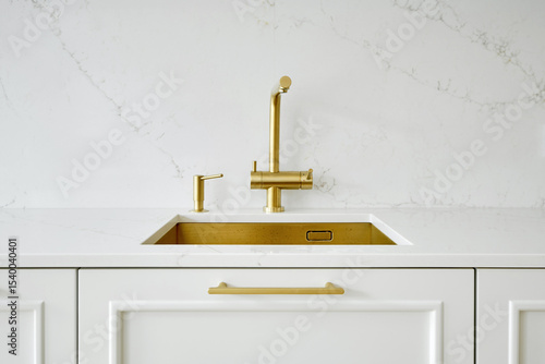 Stylish kitchen sink with gold faucet and white countertop in modern interior