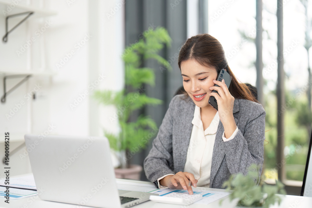 Professional Communication. Businesswoman engaging in a phone call while working on a laptop. Professional Communication. Businesswoman engaging in a phone call while working on a laptop.