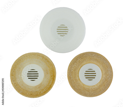 Side-by-side on a transparent background, two heavily soiled and worn water filters are positioned next to a gleaming, new white filter