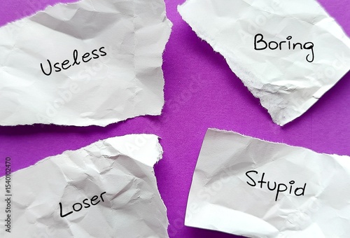 Torn crumples paper with text - LOSER STUPID USELESS BORING - Low self-esteem person tended to use negative labels to describe themselves - self-sabotage by believing unfair negative labels