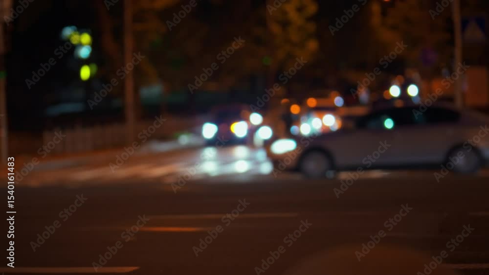Cars navigate through a bustling intersection at night while city lights illuminate the surroundings. The scene captures the energy of urban life as vehicles move through the thoroughfare Cars navigate through a bustling intersection at night while city lights illuminate the surroundings. The scene captures the energy of urban life as vehicles move through the thoroughfare