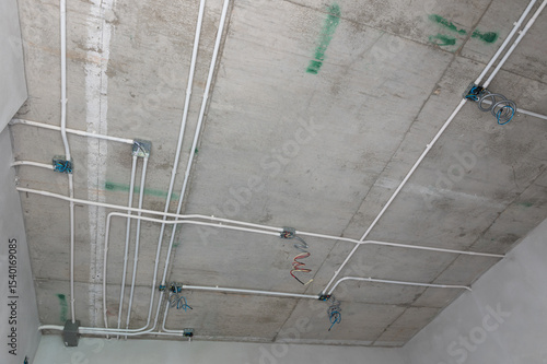 Electrical conduit system installation on exposed concrete ceiling of residential building