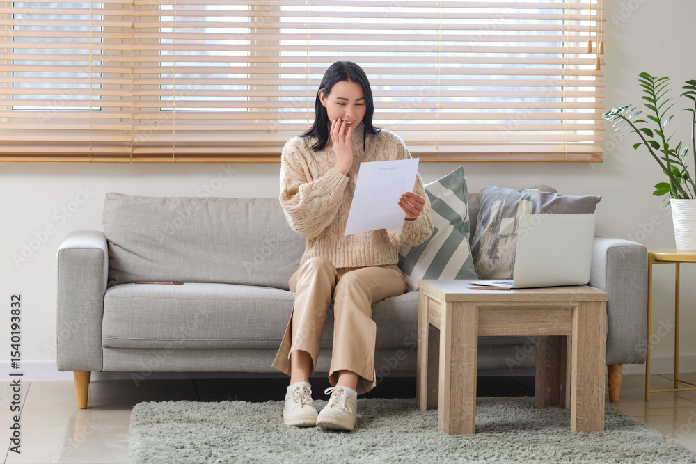© Pixel-Shot - Happy young woman with refund form sitting on sofa at home © Pixel-Shot - Happy young woman with refund form sitting on sofa at home